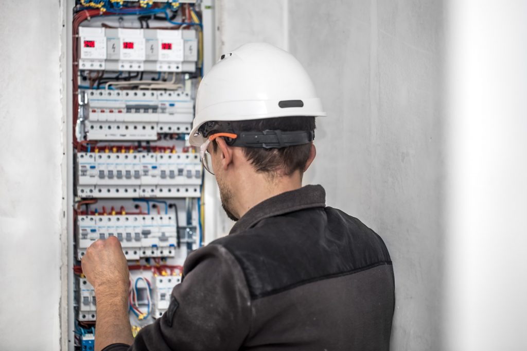 Man, an electrical technician working in a switchboard with fuses.